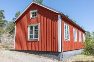 a red house with two windows on the side of it at Bergs Gård & Hållsvikens Gård in Västerljung