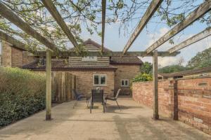 eine Terrasse mit 2 Stühlen und einem Tisch vor einem Backsteinhaus in der Unterkunft Bluebell Cottage in Ross on Wye