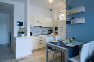 cocina con mesa y armarios blancos en Lakefront Belvedere by Garda FeWo, en Manerba del Garda