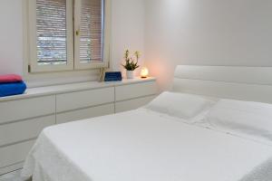 Un dormitorio blanco con una cama blanca y una ventana. en Lakefront Belvedere by Garda FeWo, en Manerba del Garda