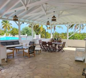 a pavilion with a table and chairs and a pool at Domaine des Tourterelles in Capesterre