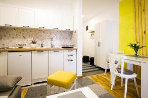 Vrnjačka BanjaにあるApartman IRISの白いキャビネットと黄色のスツール付きのキッチン