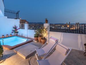 een patio met 2 stoelen en een zwembad bij Carmen de Azahar in Granada