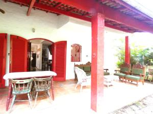 a patio with red doors and a table and chairs at Casa com muito lazer a 100m da Praia de Guaeca SP in Barequeçaba