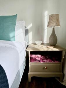 a bed with a night stand with a lamp on it at Cooden Cottage in Bexhill