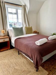 Un dormitorio con una cama con almohadas y una ventana. en Cooden Cottage, en Bexhill-on-Sea