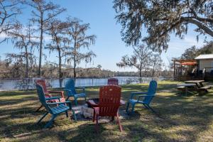 a group of chairs sitting in the grass near a lake at Suwannee Gables in Old Town