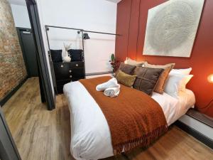 a bedroom with a large bed with an orange wall at Stunning Northern Quarter Flat in Manchester