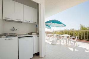 a kitchen with a table and chairs and an umbrella at Camping Villaggio Il Frutteto in Cupra Marittima