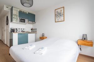 ein weißes Bett in einem Zimmer mit Küche in der Unterkunft Le 4K - Vue dégagée, Clim, Gare 10min à pied in Straßburg