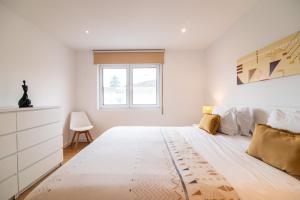 a white bedroom with a large bed and a window at Alojamento Encantador no Centro de Ponta Delgada in Ponta Delgada