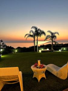 two chairs and a table in a field with palm trees at Luxury villa al mare in Calabria Diamante in Cirella