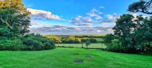 un campo de césped verde con árboles a lo lejos en OppiePlaas Self Catering Country Cottage, en Haga-Haga