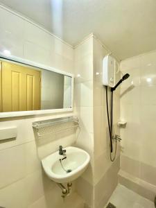 Baño blanco con lavabo y espejo en Minimalist Condo One Spatial Iloilo 2 Bedroom Unit en Iloílo