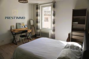 Schlafzimmer mit einem Bett, einem Schreibtisch und einem Fenster in der Unterkunft Family' appart Narbonne Centre-ville Clim Wi-fi 2 chambres in Narbonne