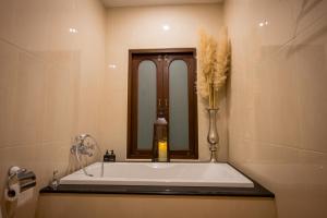 ein Badezimmer mit einer Badewanne und einer Vase aus Blumen in der Unterkunft Miranda's House Khaokho มิรันดาเฮ้าส์ เขาค้อ in Ban Lao Kok Kho