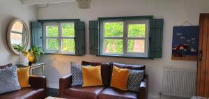 a living room with a couch and two windows at Vale View Cottages -The Coach House in Prestatyn