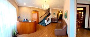 a man sitting at a counter in a room with a staircase at Hotel La Casona in Cuenca