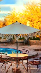 a table with an umbrella in front of a pool at Hotel Tulor in San Pedro de Atacama