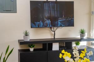 a black entertainment center with a tv on a wall at Charming refuge at Colbeck Manor in Old Harbour