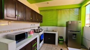 eine Küche mit Holzschränken und grünen Wänden in der Unterkunft QORY WASY in Cusco