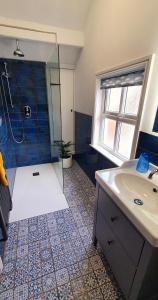 a bathroom with a shower and a sink and a mirror at Vale View Cottages -The Coach House, Great location in Prestatyn! in Prestatyn
