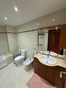 uma casa de banho com 2 lavatórios, um WC e um espelho. em La Presidencia em La Coruña