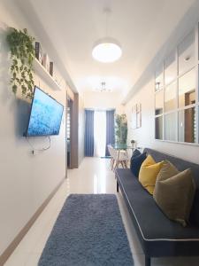 a living room with a couch and a tv on a wall at SMDC Coast Residences near PICC World Trade Center MOA in Manila