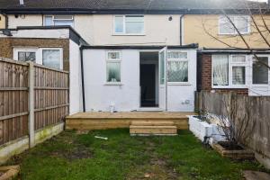 a house with a wooden porch and a fence at The Dagenham Park Place - Dazzling 3BDR House with Garden in Dagenham