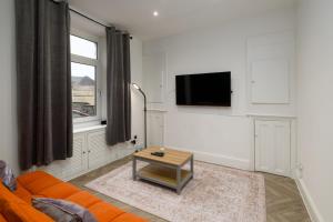 a living room with an orange couch and a table at Inviting House near Skewen Park in Skewen