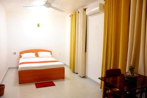 a bedroom with a bed and a desk and curtains at Ranathisara Grand Hotel in Kurunegala