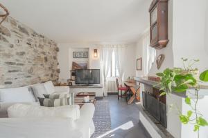 Giuliano's House - Amazing Lake View by Rent All Como في لاليو: غرفة معيشة بأثاث أبيض وجدار حجري