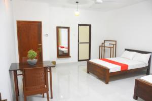1 dormitorio con cama, mesa y espejo en Ranathisara Grand Hotel en Kurunegala