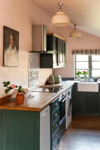a kitchen with green cabinets and a sink at Apple Cottage - Vivre Retreats in Wimborne Minster