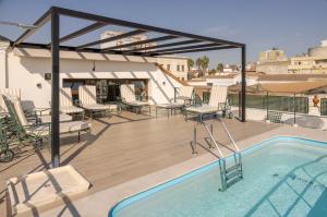 a deck with chairs and a swimming pool on a roof at Hotel Ilunion Mérida Palace in Mérida