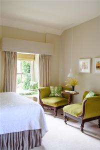 een slaapkamer met een bed en 2 stoelen en een raam bij Gregans Castle Hotel in Ballyvaughan