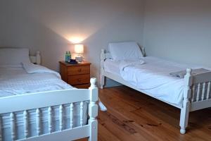 twee witte bedden in een slaapkamer met een houten vloer bij Valentia Island Escape in Valentia Island