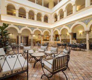 a hotel lobby with tables and chairs and a building at Hotel Ilunion Mérida Palace in Merida