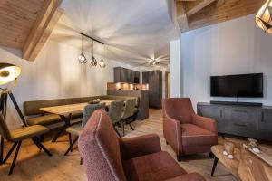 sala de estar con mesa, sillas y TV en AlpenParks Hotel & Apartment Taxacher, en Kirchberg in Tirol