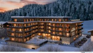 um grande edifício na neve com árvores em AlpenParks Hotel & Apartment Taxacher em Kirchberg in Tirol