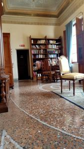 a living room with chairs and a table and bookshelves at Dimora del Conte in Pisa