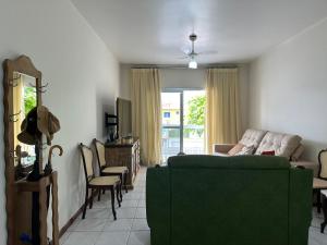 ein Wohnzimmer mit einem grünen Sofa und einem TV in der Unterkunft Apto 2Q completo em frente a praia Ponta da Fruta in Ponta da Fruta