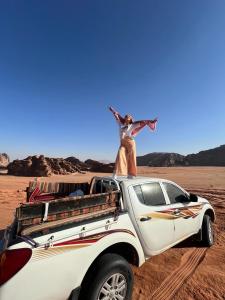 Una mujer parada en la parte trasera de un camión blanco en el desierto en Bubble RumCamp, en Wadi Rum