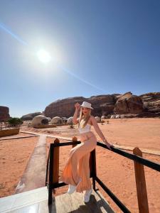 a woman in an orange dress leaning on a fence at Bubble RumCamp in Wadi Rum