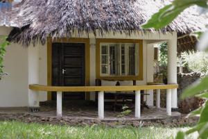 eine kleine Hütte mit einer Bank davor in der Unterkunft Diani Peaceful Garden in Diani Beach