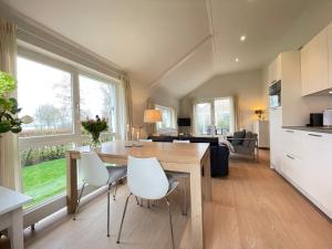 uma cozinha e sala de estar com mesa e cadeiras em Watervilla de IJsvogel by Droomvilla em Langweer