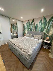 a bedroom with a large bed with leaves painted on the wall at MYSTAY BERLIN Müggelheim in Berlin