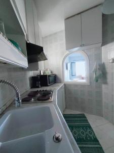 uma cozinha branca com um lavatório e uma janela em Spectacular Port View and Beach Apartment KANTAOUI SOUSSE em Port El Kantaoui