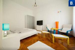 ブダペストにあるJókai Apartmentのベッド1台、椅子2脚、テレビが備わる客室です。