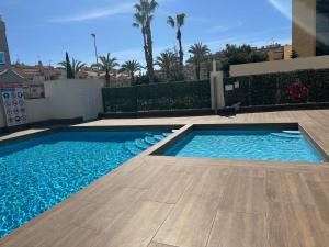 a swimming pool with blue water in a yard at Prestige Sunny Terrace Apartment - Torrevieja in Torrevieja
